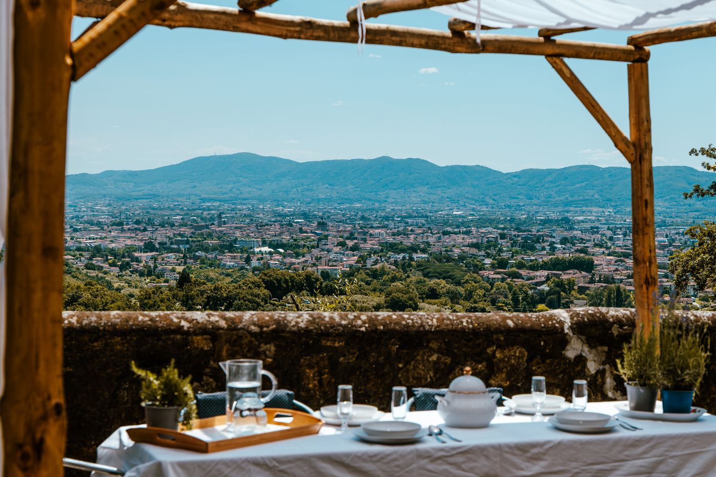 Tavola apparecchiata sotto la pergola con vista su Pistoia