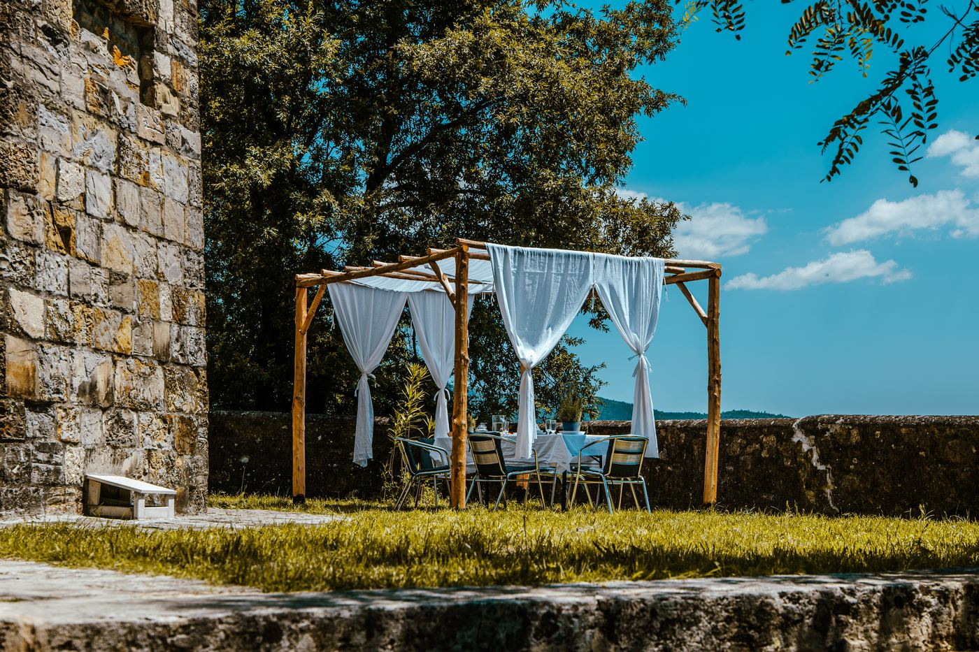 Pergola con tende bianche nel giardino della torre