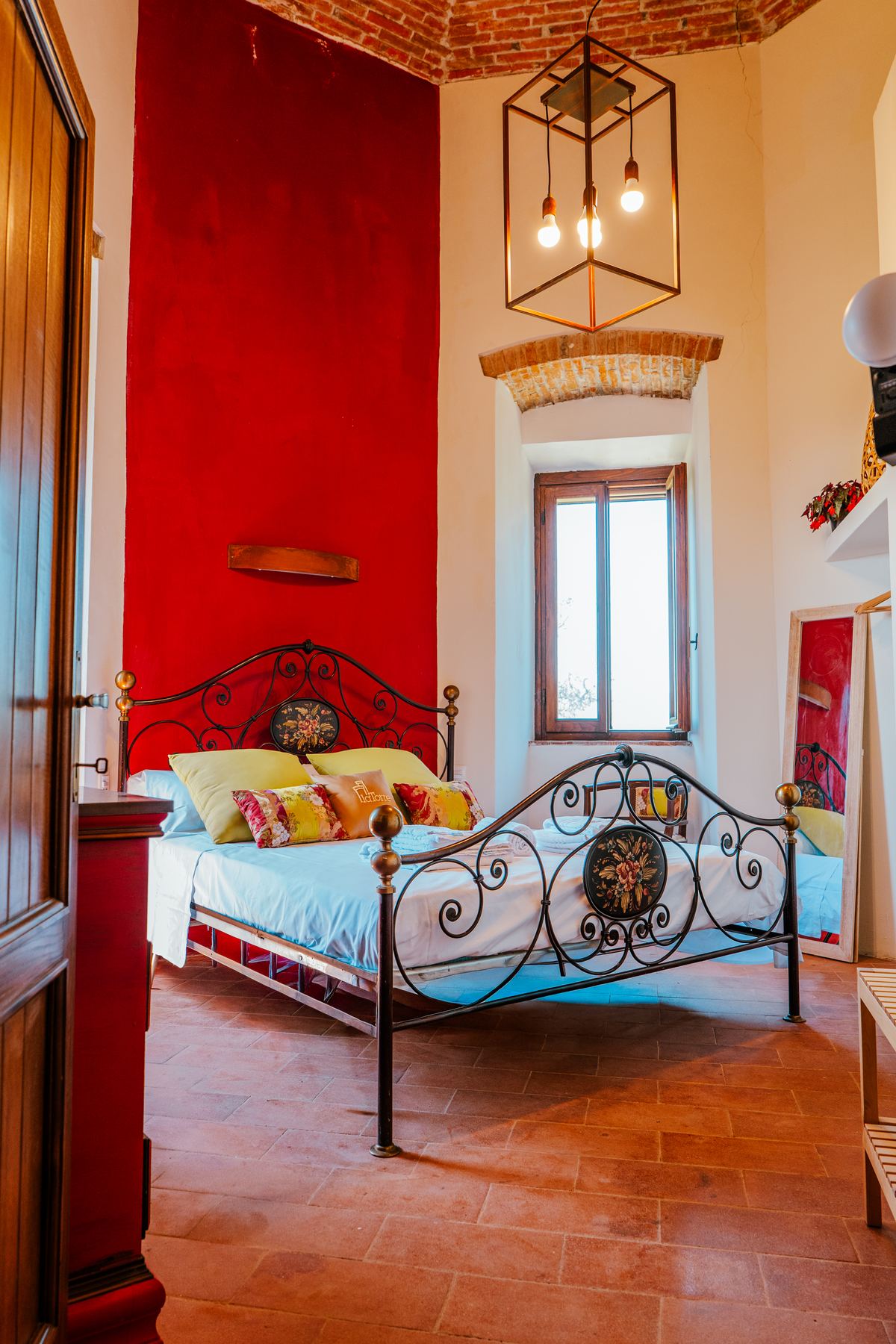 Camera con letto in ferro battuto e parete rossa